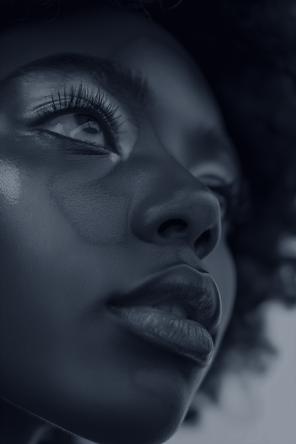 A black and white close up of a woman with afros, from the left side slightly below her chin